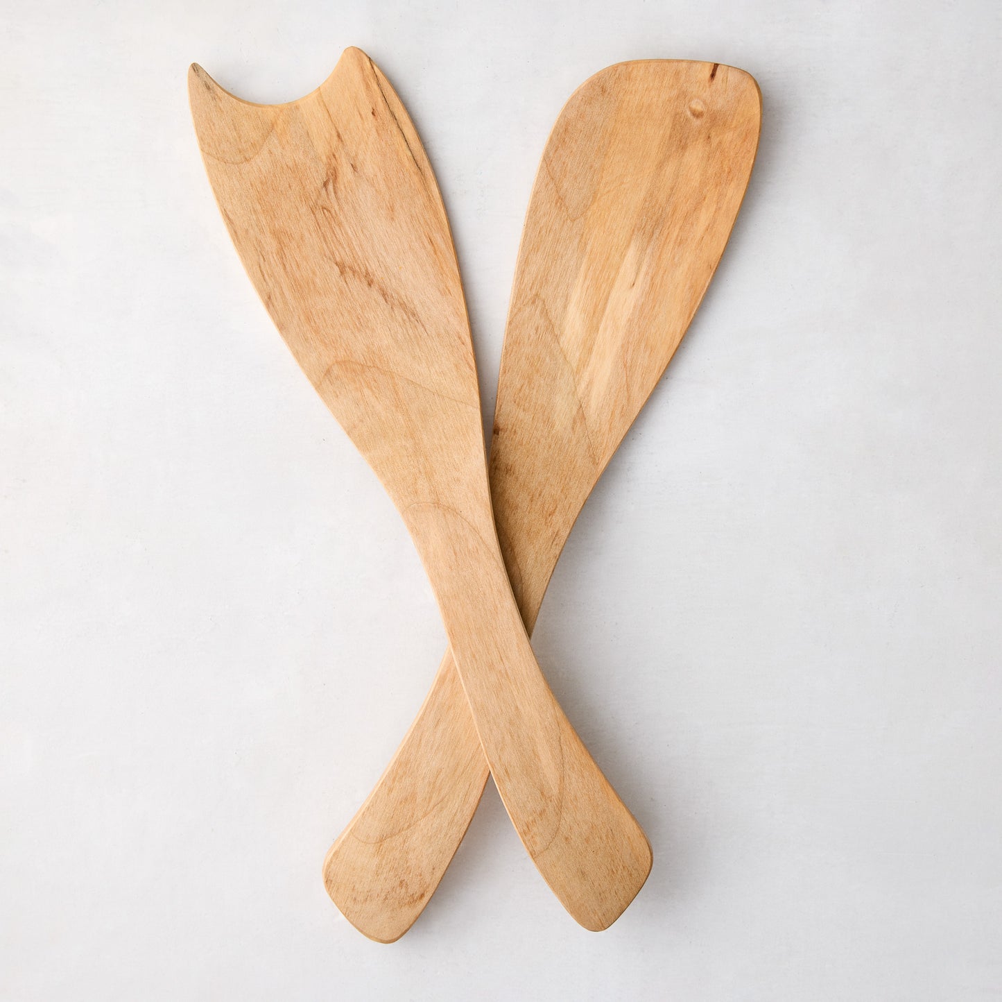 Rustic spalted maple wood salad servers, light brown with unique grain patterns, crossed on white.