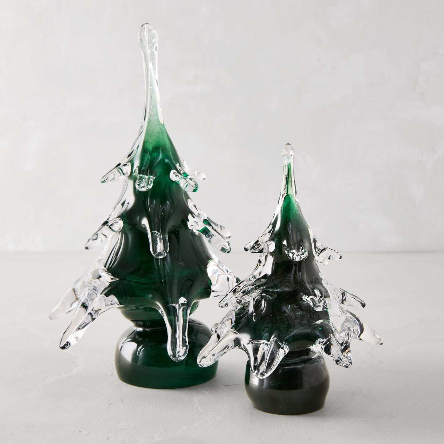 Two handblown green glass Christmas trees, one 7"H, with clear glass branches.