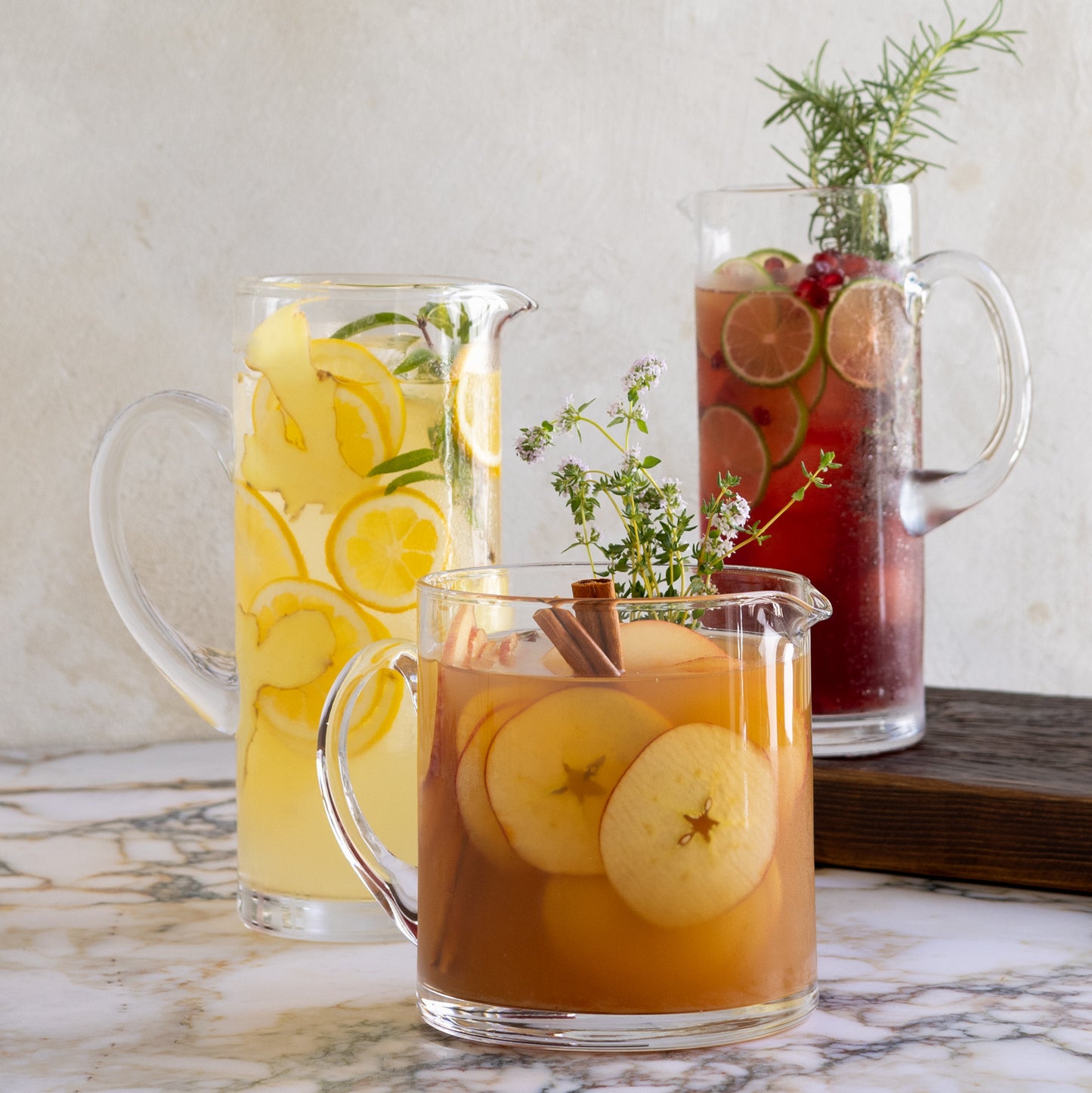 Three Soho Short Glass Pitchers, clear hand-blown glass, filled with various fruit drinks.