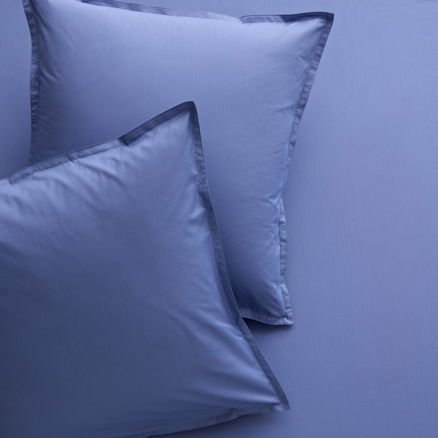 Set of 2 Steele Blue Italian Percale Euro Shams with envelope closures, shown on matching bedding.