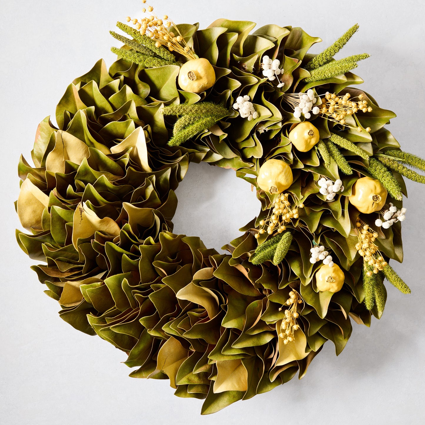 Sunlit Meadow Wreath with green magnolia leaves, chartreuse yellow pomegranates, and yarrow sprigs.