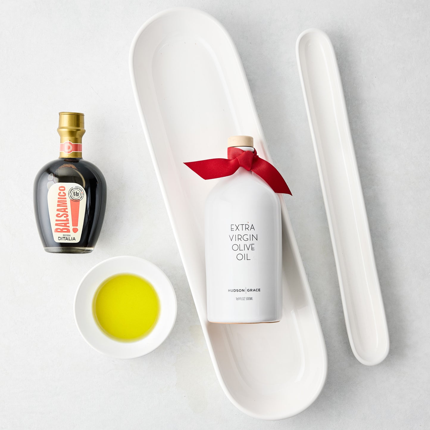 White ceramic baguette and olive trays with balsamic vinegar, olive oil, and a dipping bowl.