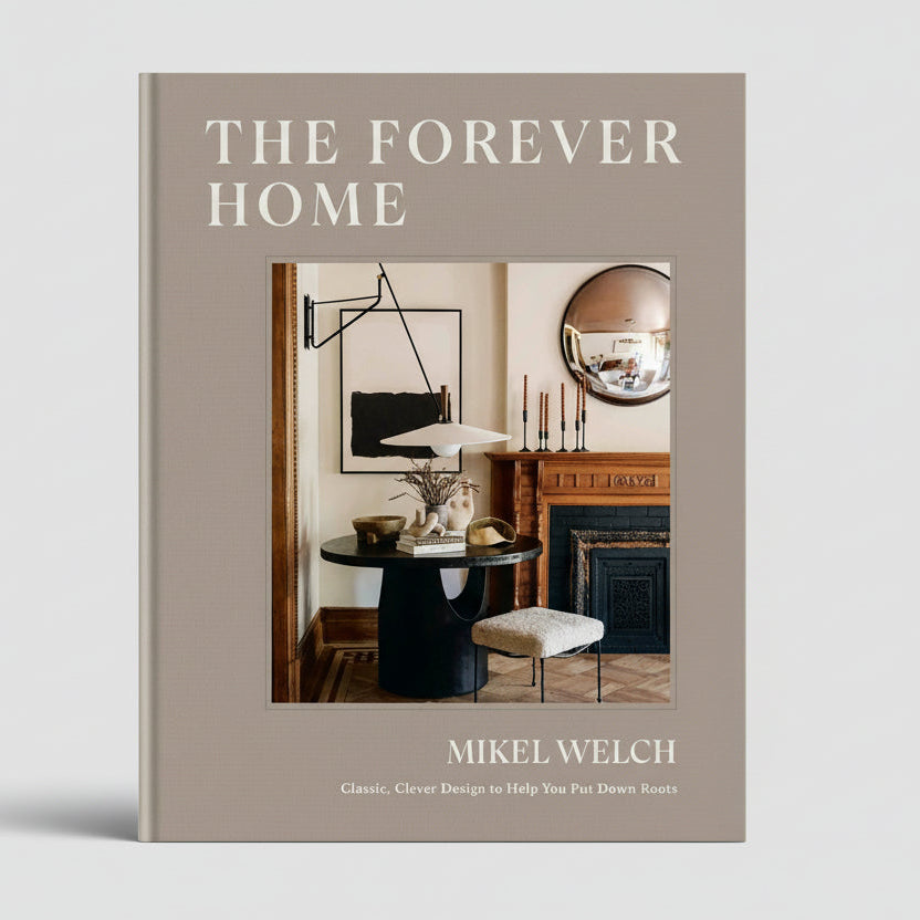The Forever Home" coffee table book, beige hardcover with interior design image, by Mikel Welch.
