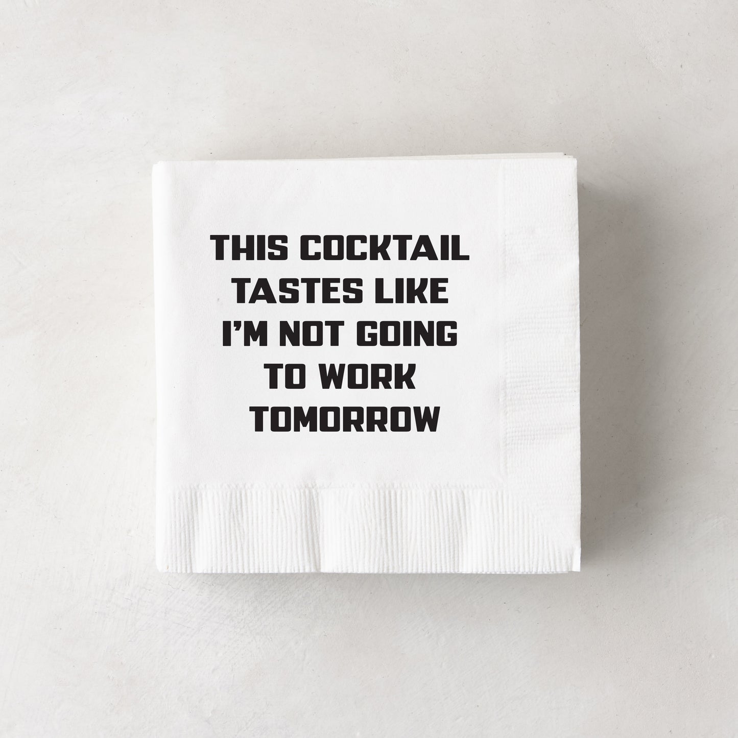 White paper cocktail napkins with "THIS COCKTAIL TASTES LIKE I'M NOT GOING TO WORK TOMORROW" in black text.