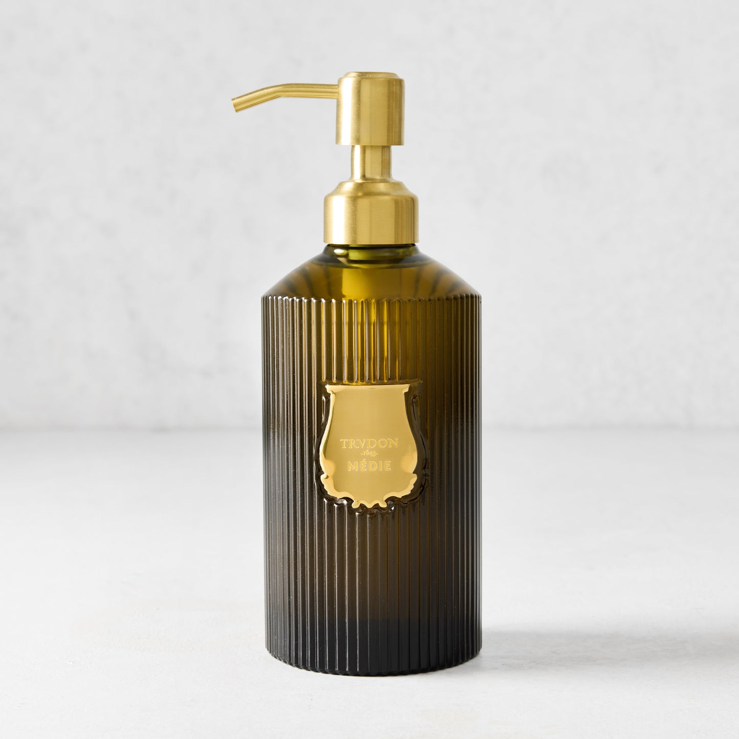 Trudon Medie 350ml liquid hand soap in a ribbed dark green glass bottle with a gold pump and label.