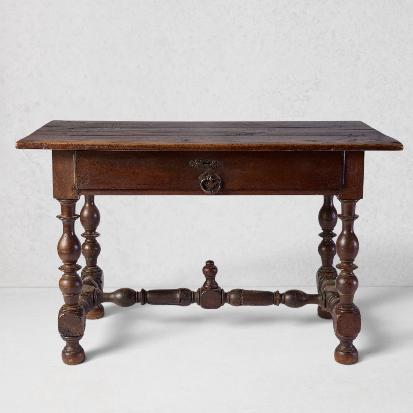 Vintage Louis XIII dark wood desk with turned legs, single drawer, and central cross-support decorative knob.