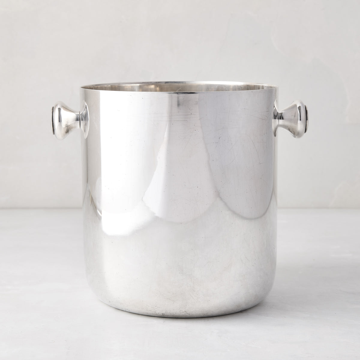 Vintage silverplate champagne bucket with two side handles and a polished finish on a light background.