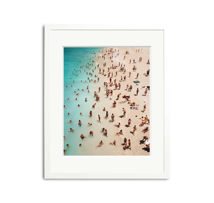 We Forest Framed Wall Art Print: Aerial view of a crowded beach with turquoise water, white sand, and many people, in a white wooden frame with a mat.