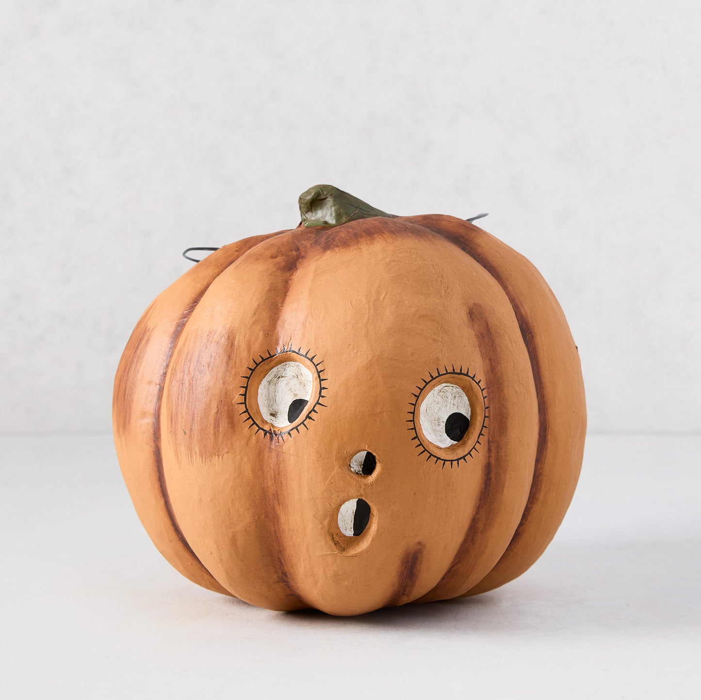 Vintage-style orange papier-mâché pumpkin candy bucket with a distressed finish and surprised face, 7.25 inches tall.