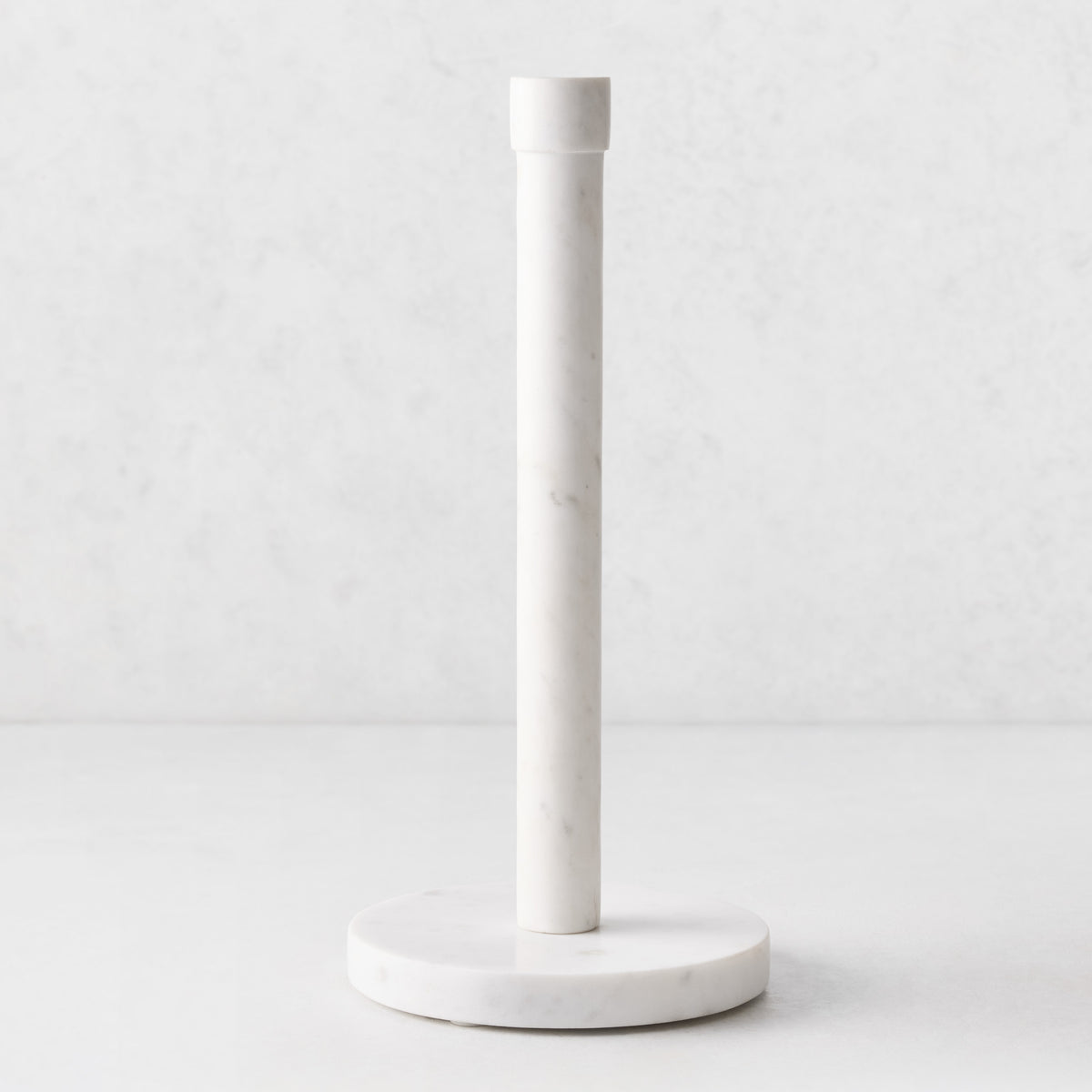 White marble paper towel holder with a heavy circular base and sleek vertical pole, 13 inches tall.