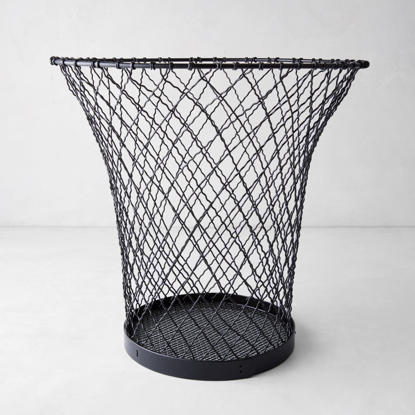 Black wire waste bin made of woven iron, 12"H, with a flared top and solid base.