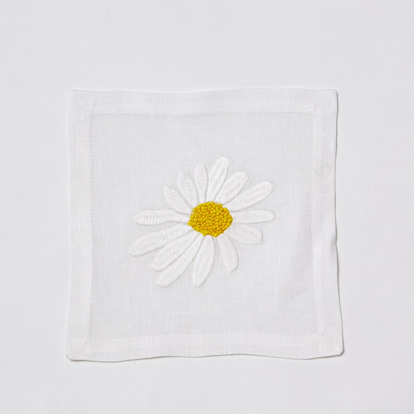 White linen 6" square coaster with hand-embroidered white and yellow daisy.