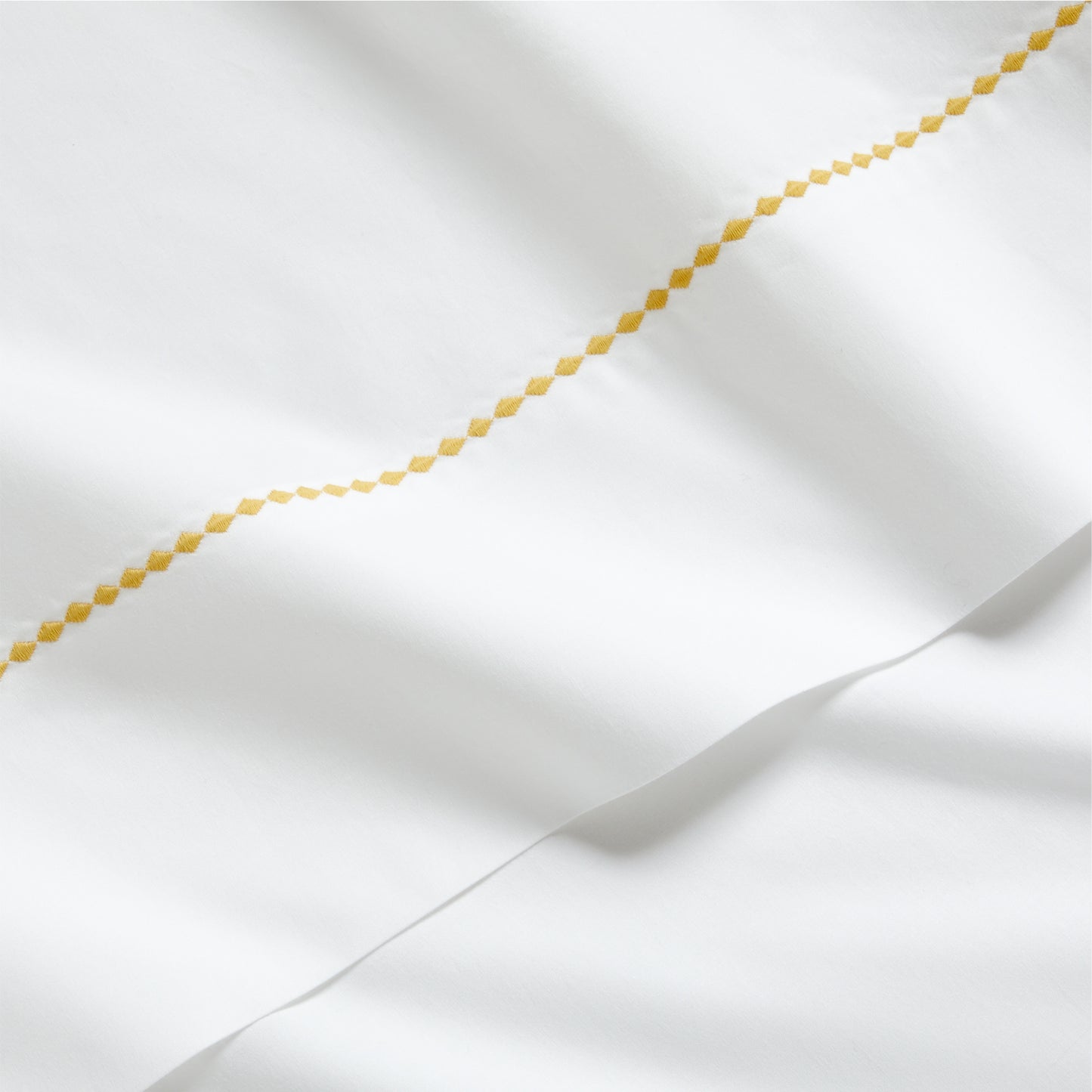 White percale sheet set with a yellow diamond embroidered border.