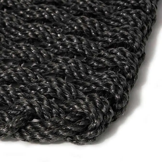 Close-up of a handwoven charcoal braided rope doormat, showing its textured, durable weave.