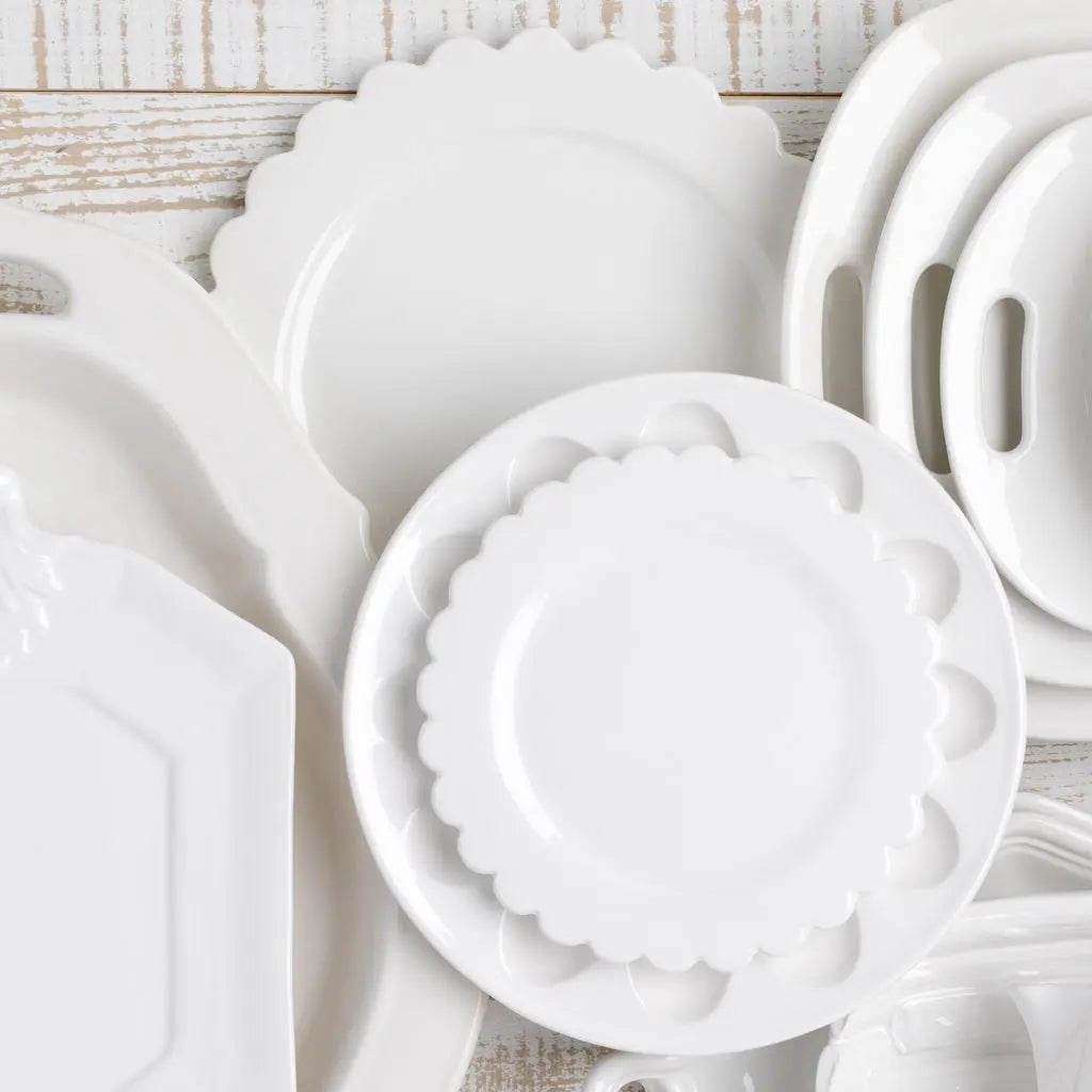 White ceramic deviled egg platter with scalloped edges, 11" diameter, shown among other white serveware.