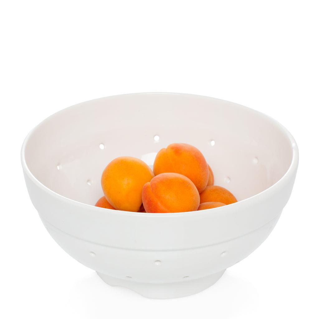 Hudson Grace white ceramic colander, vintage-inspired, with apricots inside.