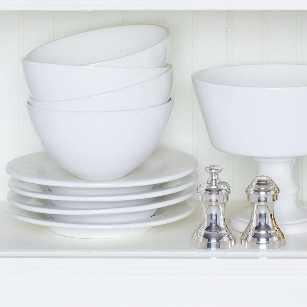 Creamy white Italian ceramic compote, footed bowl, and stacked plates with two silver shakers.