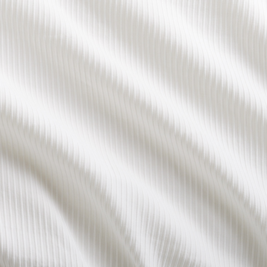 White ribbed cotton matelassé coverlet with subtle texture and soft folds.
