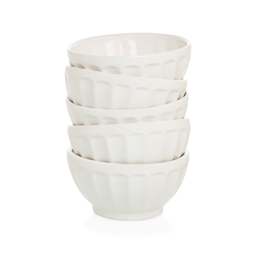 Stack of five creamy white ceramic latte bowls with fluted sides.