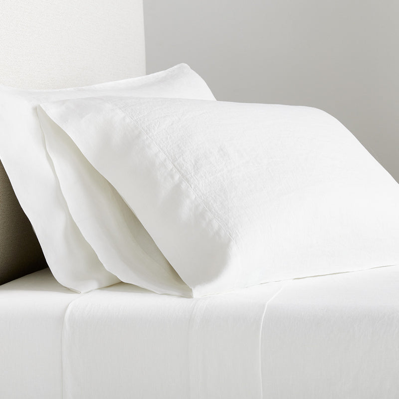 White Washed Linen Sheet Set with two pillowcases and a flat sheet on a bed.