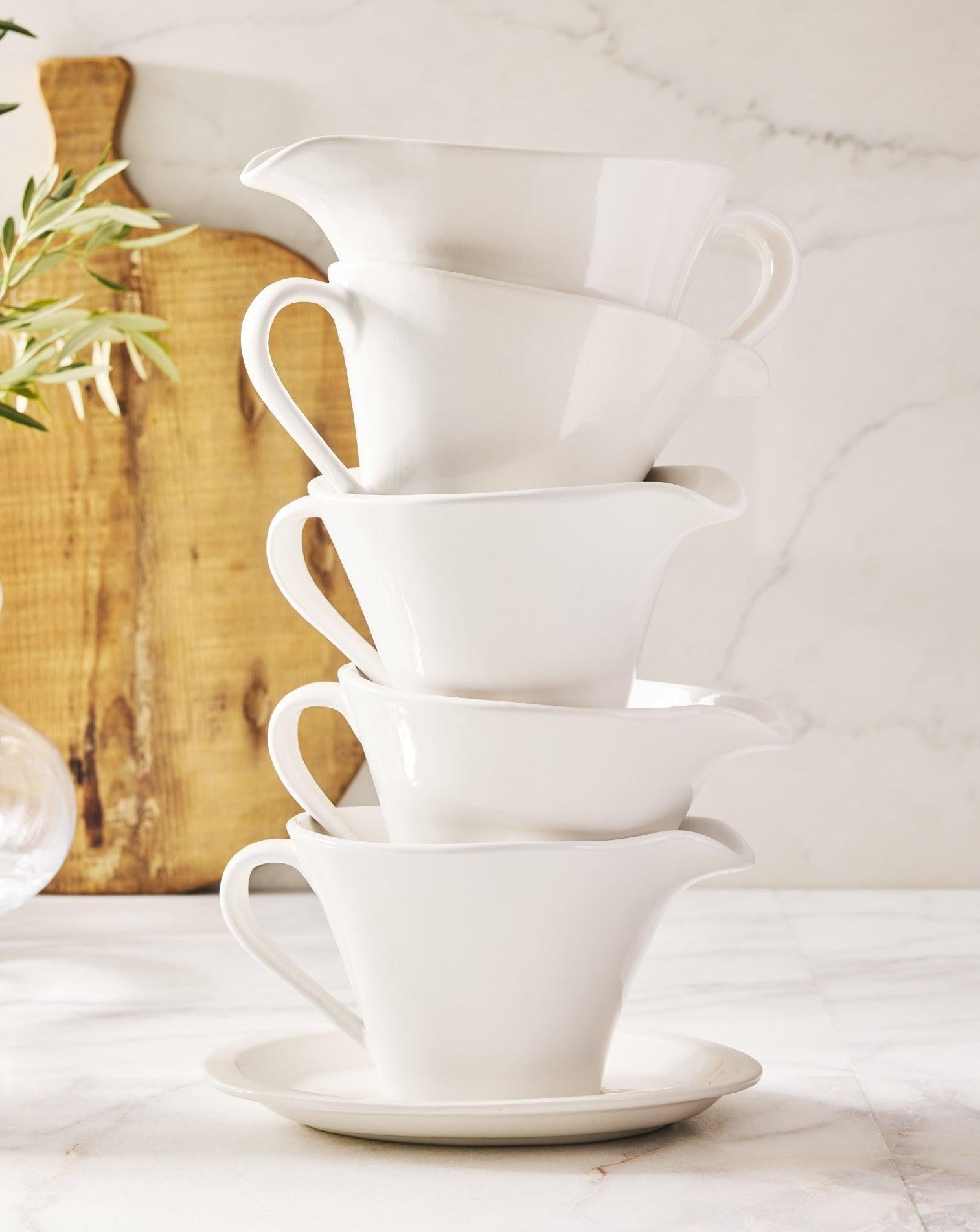 Stack of white ceramic gravy boats for Thanksgiving essential serveware.