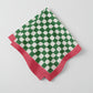Green and white checkered napkin with red border on a white background