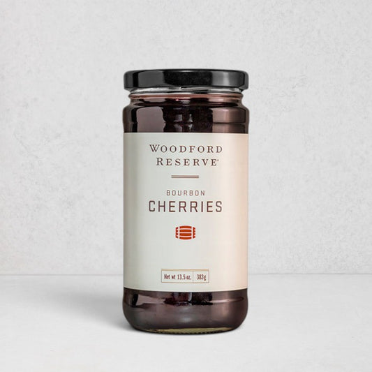 Woodford Reserve Bourbon Cherries in a clear glass jar with a black lid and white label.