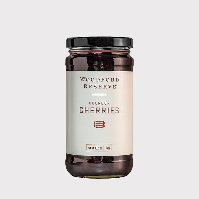Woodford Reserve Bourbon Cherries in a clear glass jar with a black lid and white label.