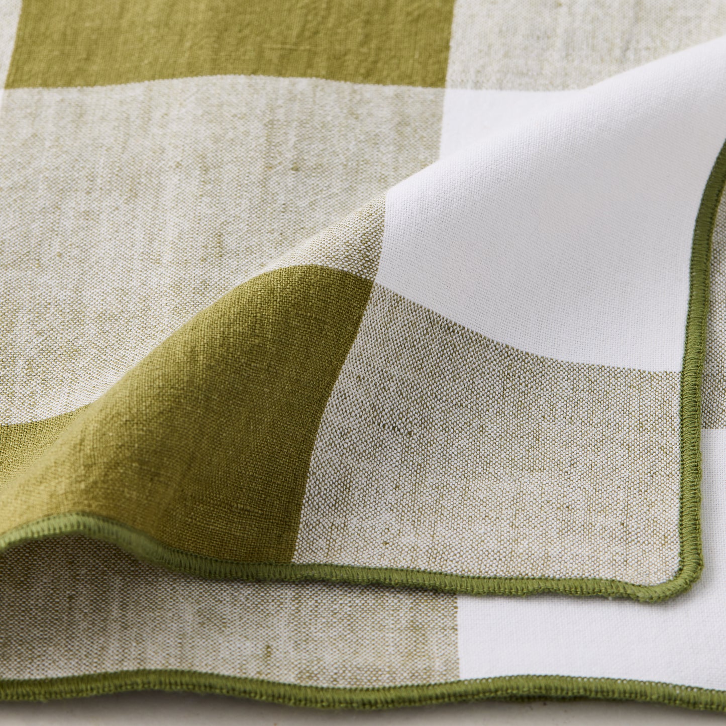Aloe Green Buffalo Check Linen Napkin, 20" x 20", folded with green stitched edge.
