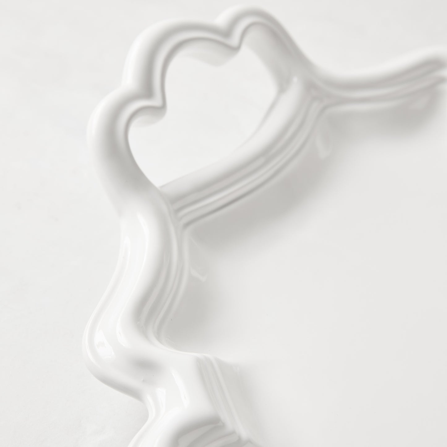 White ceramic Amalfi serving platter with scalloped edge and integrated heart-shaped handle.