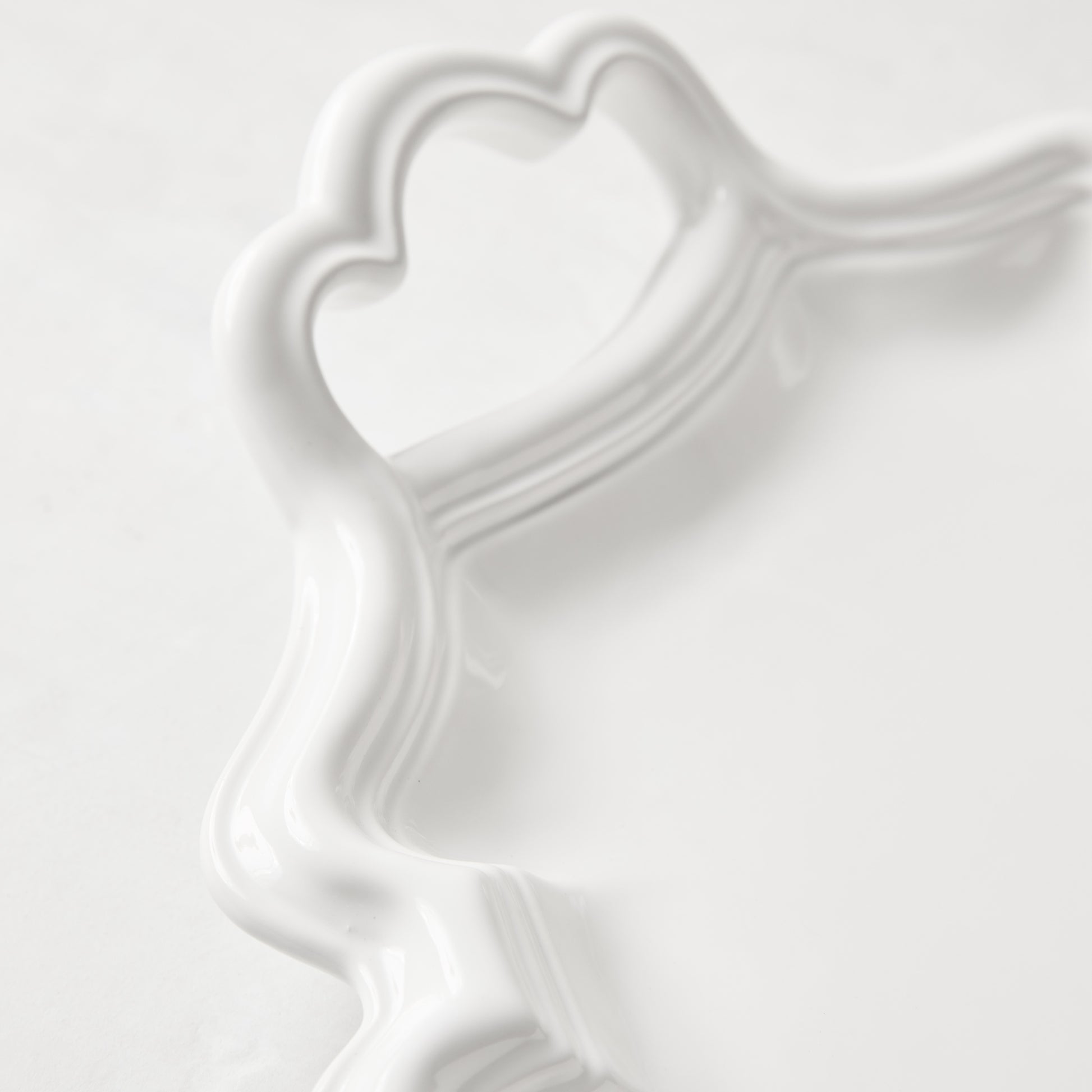 White ceramic Amalfi serving platter with scalloped edge and integrated heart-shaped handle.