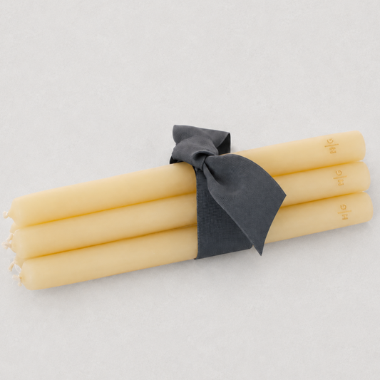 Three thick, 22-inch amber taper candles with gold HG logo, tied together with a grey ribbon on a white background.