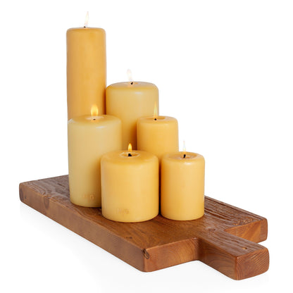 HG Amber unscented paraffin pillar candles, various sizes, on a wooden board.