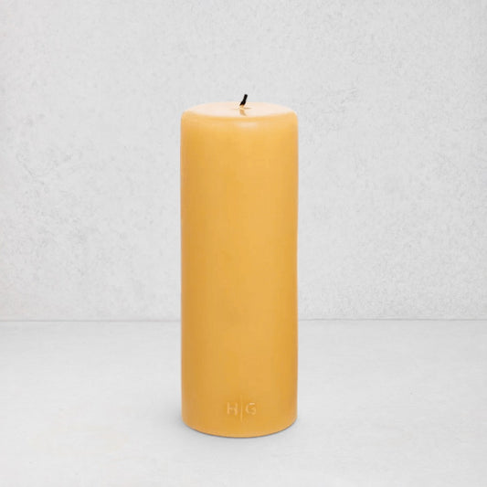 HG Amber Unscented Pillar Candle, 3"x8", with a gold embossed HG logo and black wick.