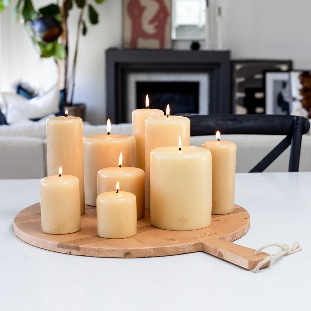 HG Amber Unscented Pillar Candle, 5"x6", hand-dipped paraffin, gold HG logo, on a wooden tray.