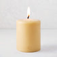 5" x 6" amber unscented pillar candle with a lit cotton wick and gold HG logo embossed on the front.