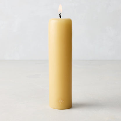HG Amber Unscented Taper Candle, 7" x 1 3/4" hand-dipped paraffin pillar with gold HG logo, lit wick.
