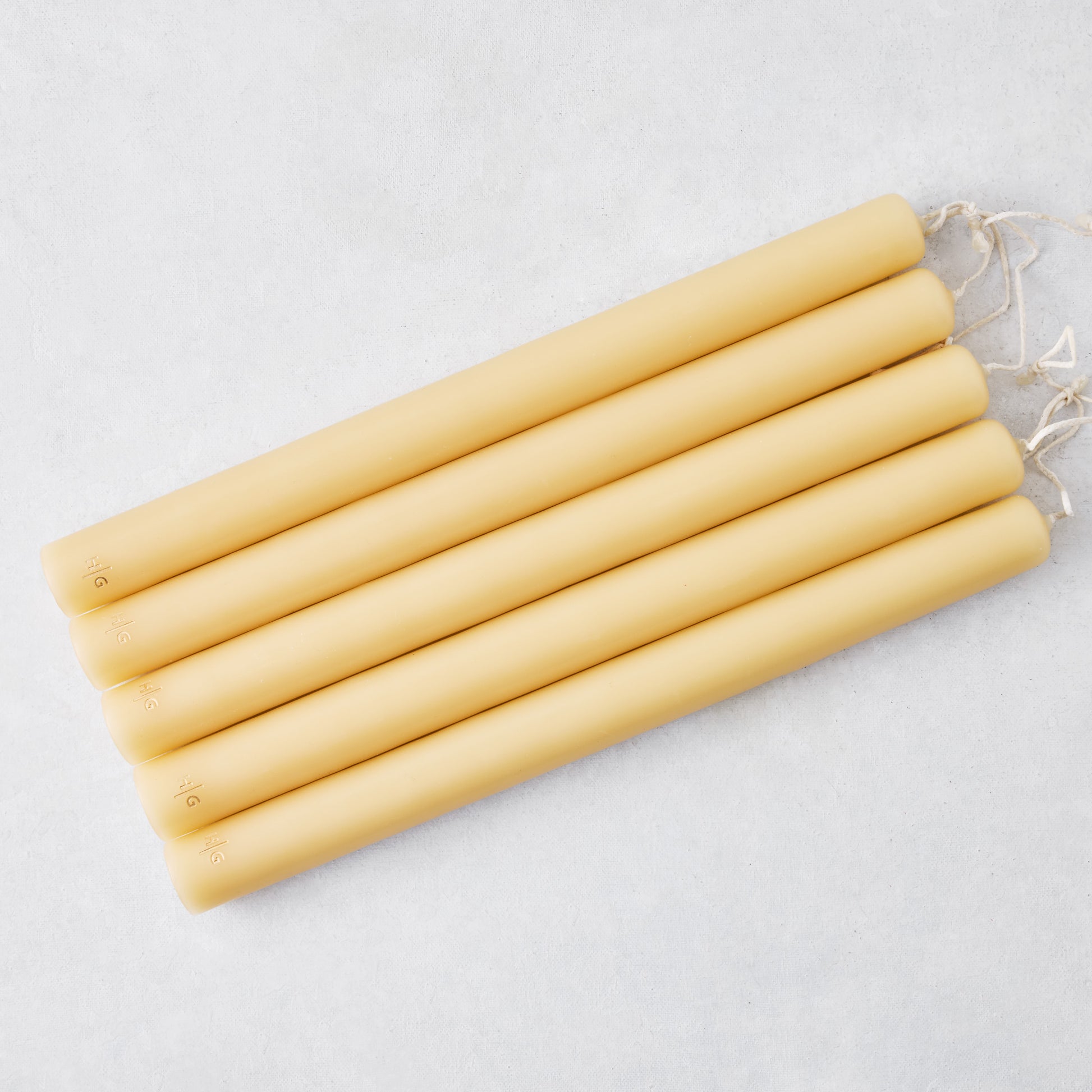 Set of five 12-inch amber unscented taper candles with gold HG logo embossing and cotton wicks.