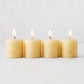 Set of four 2-inch amber unscented votive candles with lit wicks and embossed gold HG logo on a white background.