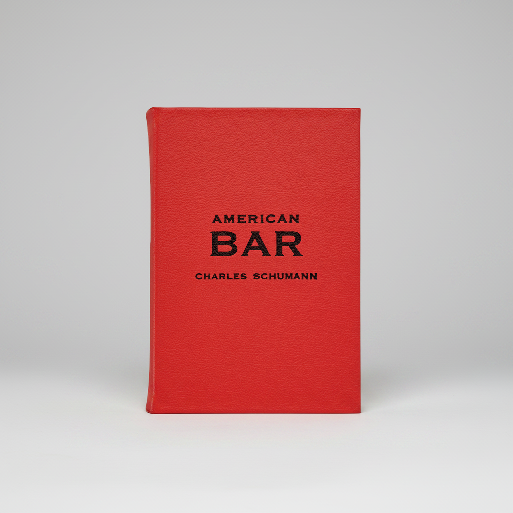 Red leather-bound American Bar book by Charles Schumann with black text.