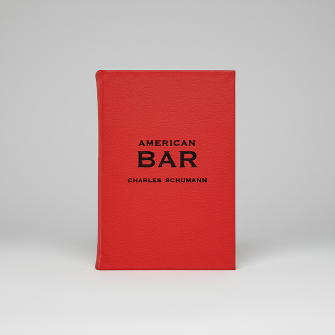 Red leather-bound American Bar book by Charles Schumann with black text.