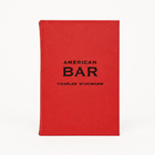 American Bar by Charles Schumann, a red leather-bound cocktail recipe book with black embossed text on the cover.