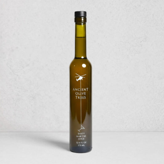 Ancient Olive Trees Dirty Martini Juice in a tall, dark green glass bottle with a black cap.