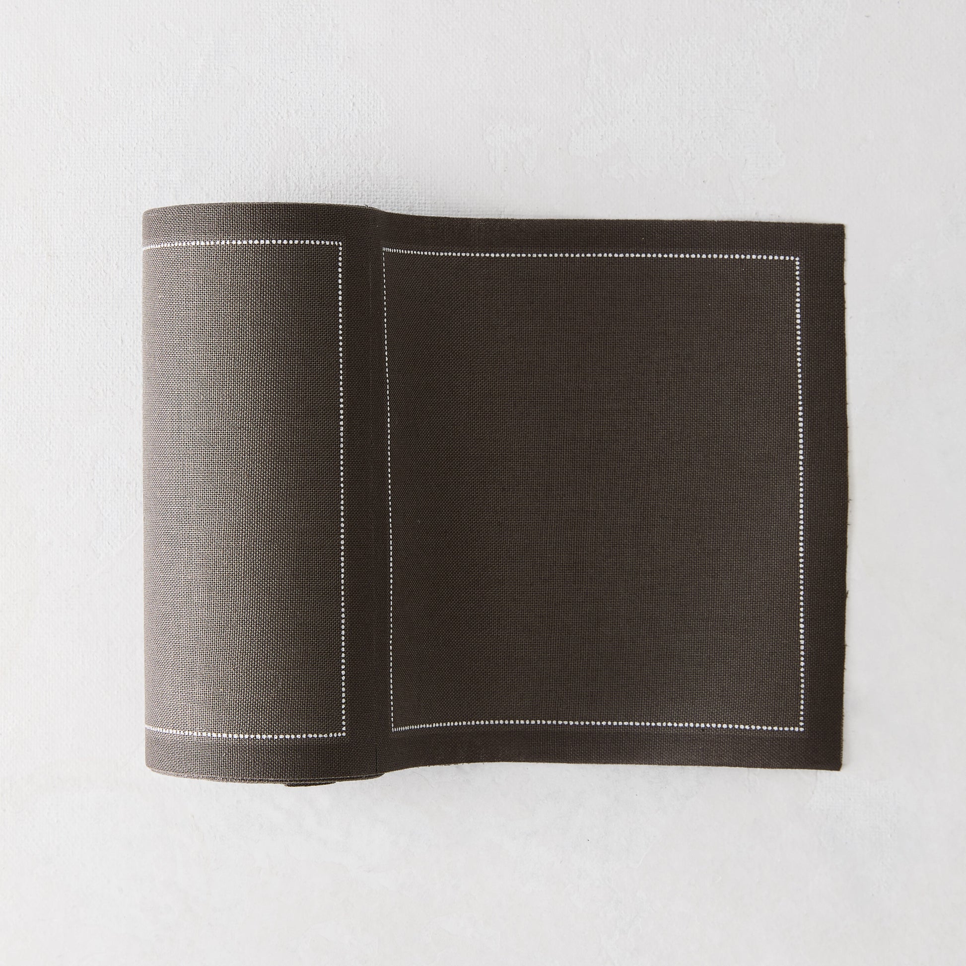 Anthracite grey tear-off cotton cocktail napkins, roll of 50, with a white stitched border.