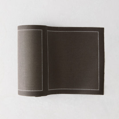 Anthracite grey tear-off cotton cocktail napkins, roll of 50, with a white stitched border.