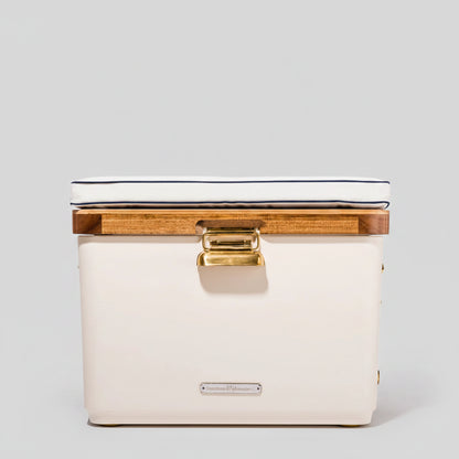 Antique white Hemingway cooler with acacia wood lid, white cushion, and brass hardware.