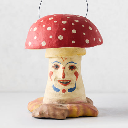 Vintage-style papier-mâché mushroom candy bucket with red polka-dot cap and hand-painted clown face on a cream stem.