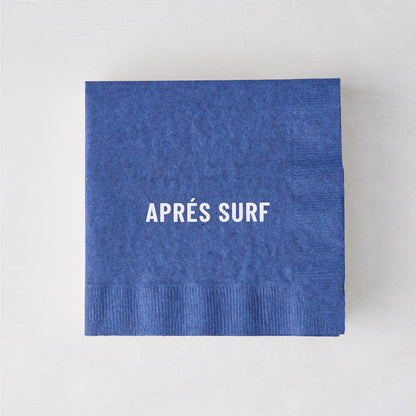 Blue 5.5" square paper cocktail napkin with "APRÉS SURF" in white text.