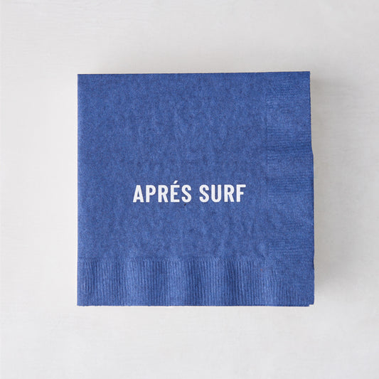Blue 5.5" square paper cocktail napkin with "APRÉS SURF" in white text.