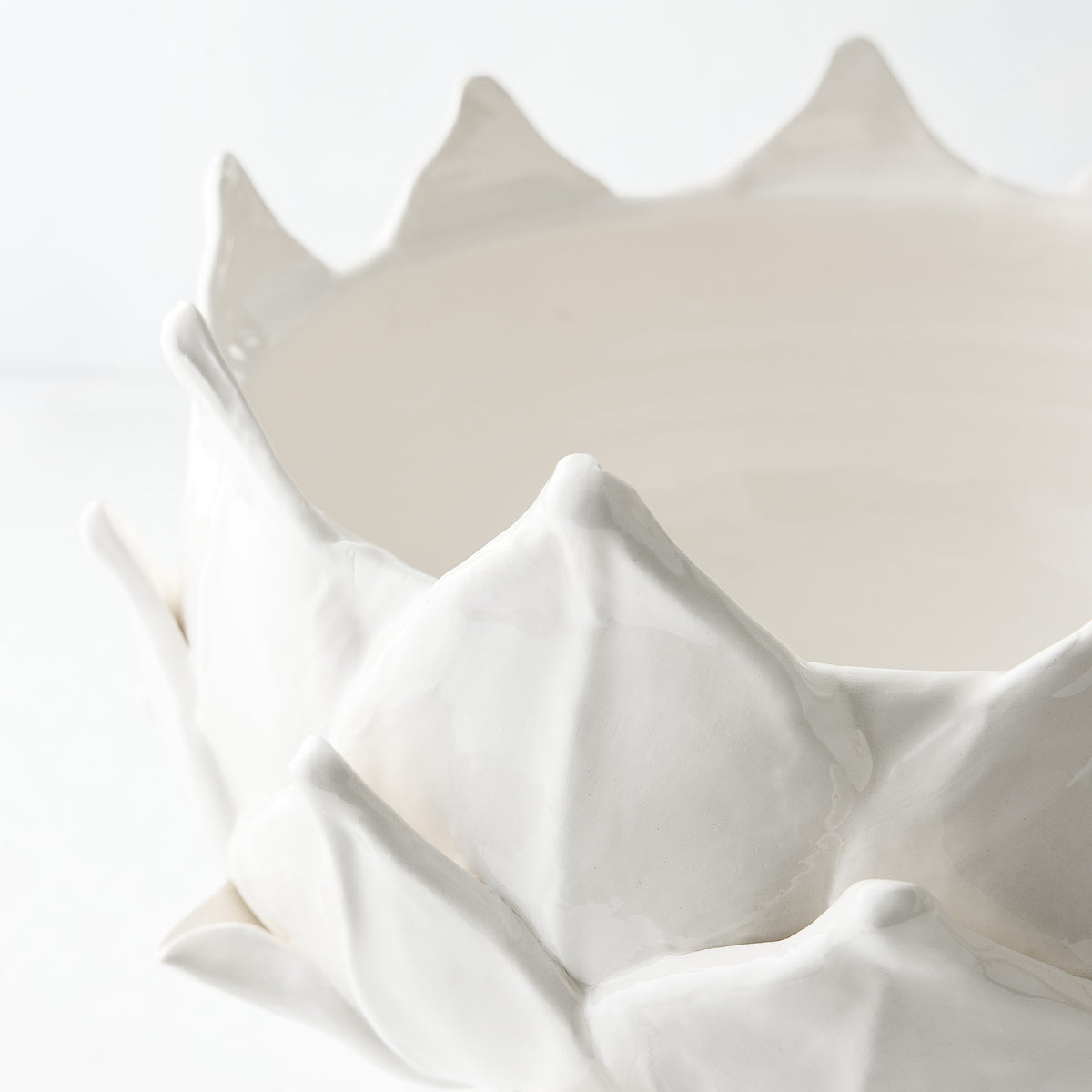 White ceramic footed bowl shaped like an artichoke with layered leaf detailing, 14-inch diameter.